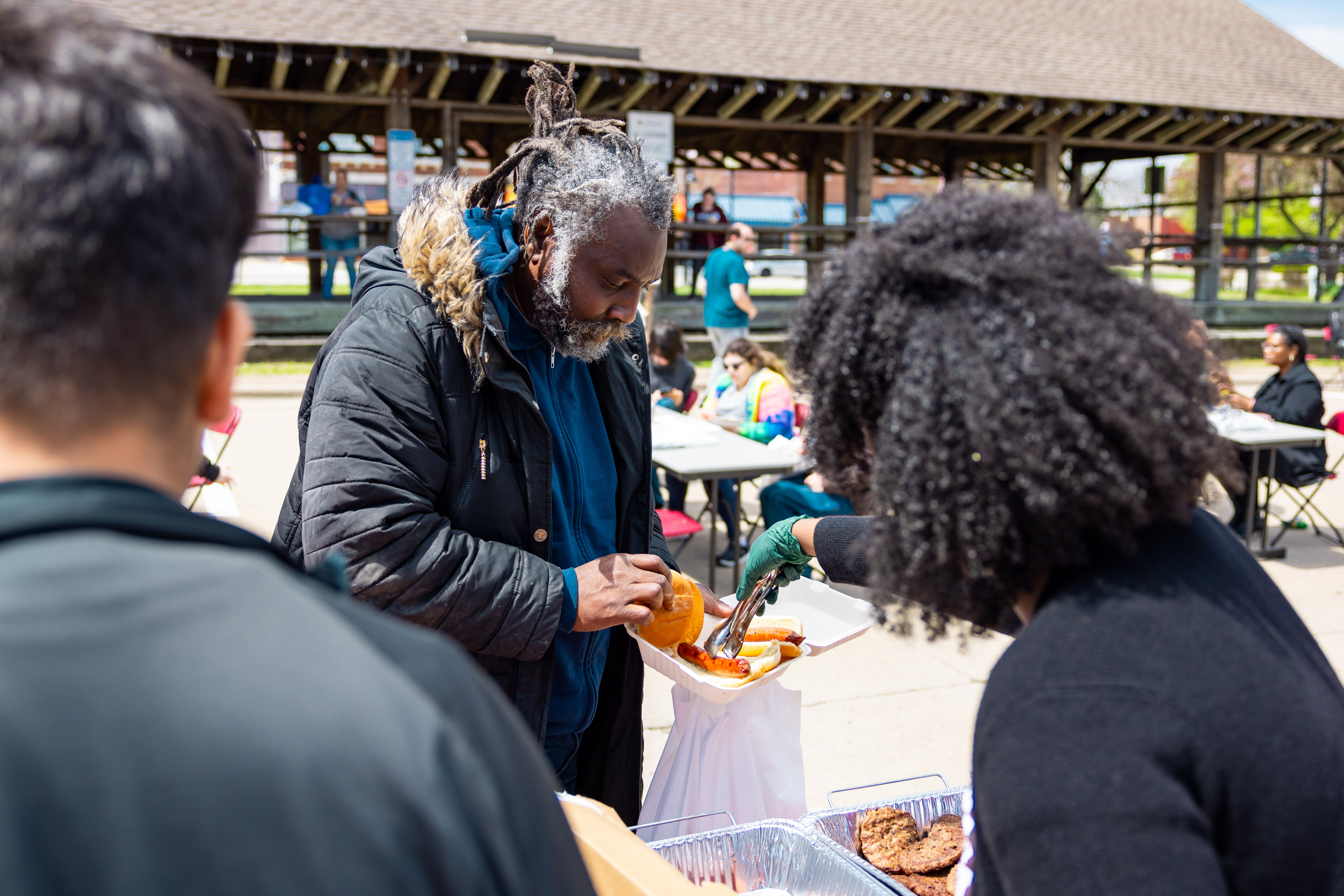 A volunteer serves a community member a plate of food on a sunny day at the old train depot in downtown Carbondale.