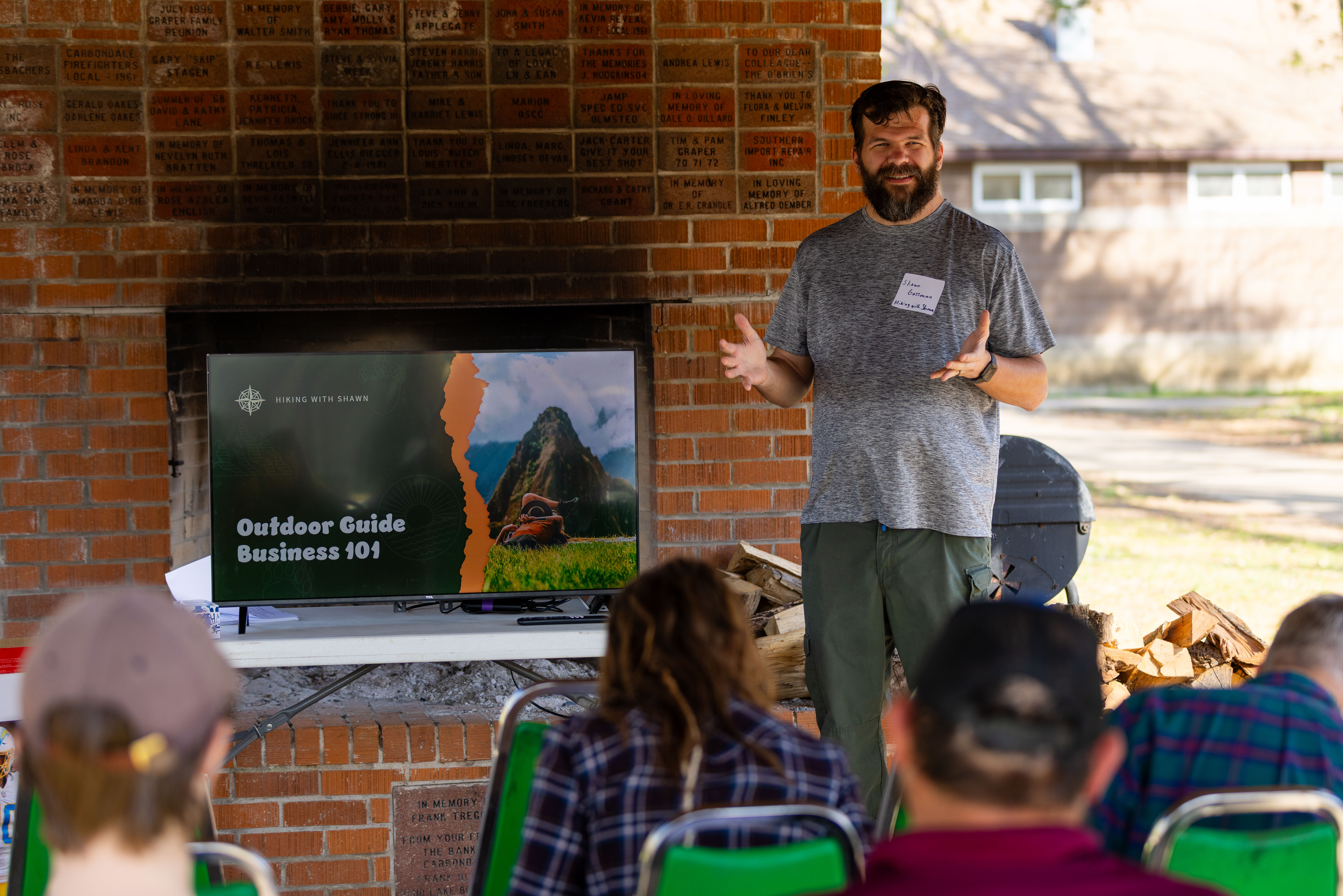 A picture of a presenter talking to a group under a pavilion. 