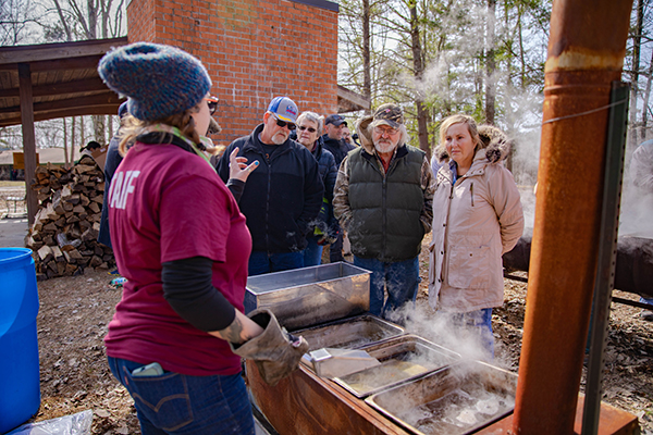 A Touch of Nature staff member explains how to make maple syrup over a steamy boiling container of maple sap.