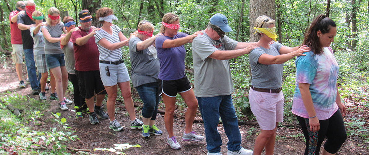 group of people walking in a line with hands on each other's shoulders