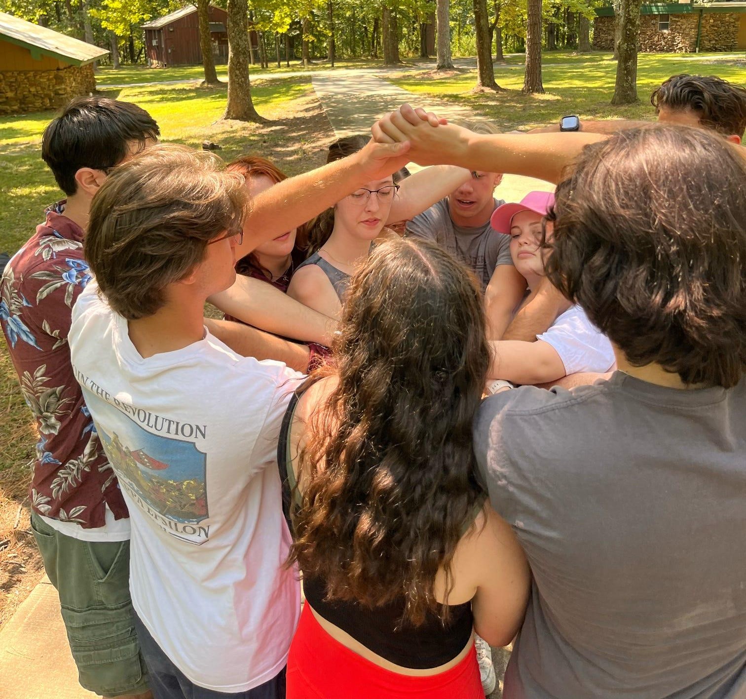 A group of college student participate in a team building excerise outside.