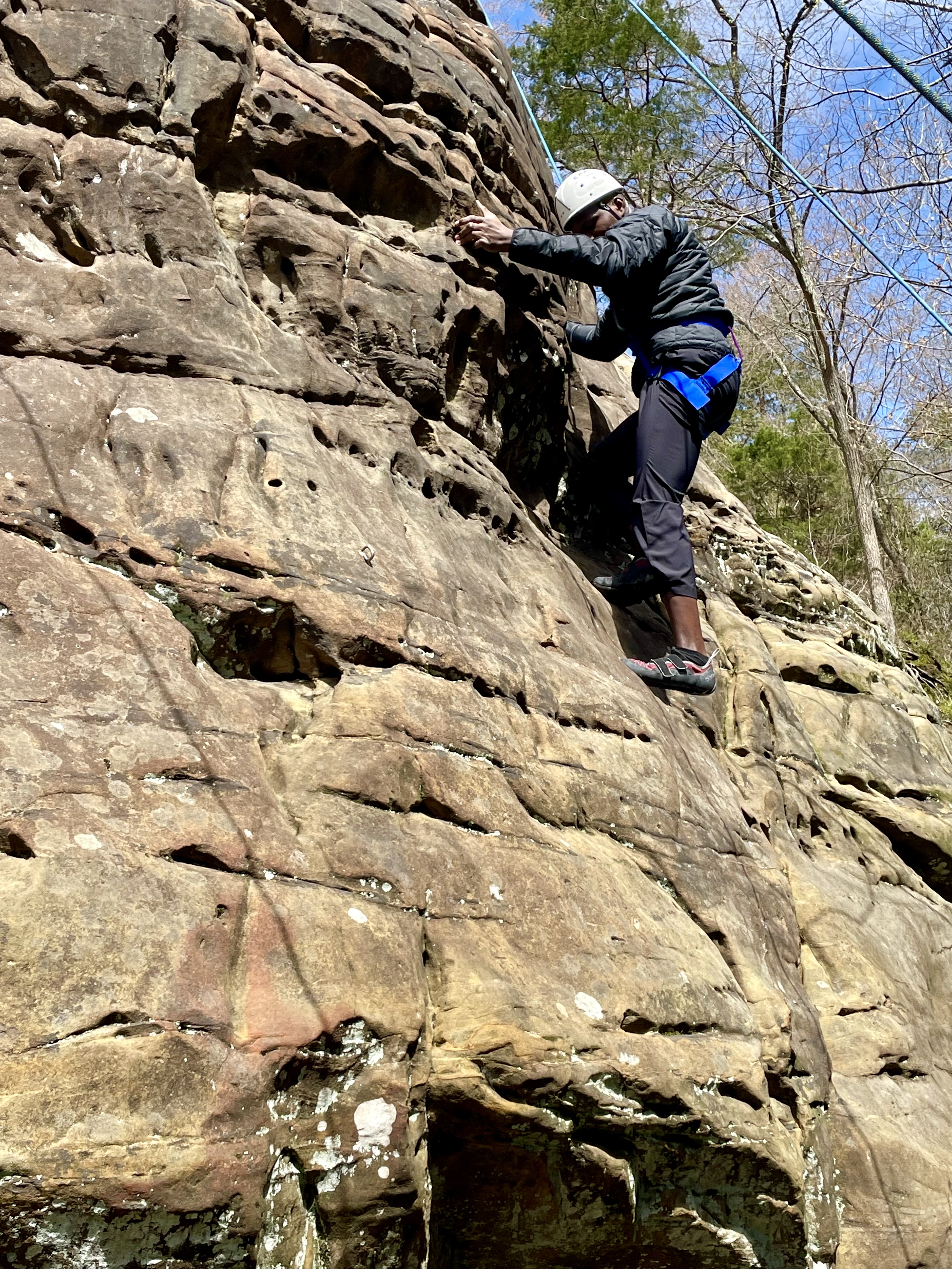 A climber scales sandstones bluff on a sunny day at Giant City State Park.